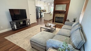 Ein Wohnzimmer mit einer Couch, Couchtisch, Fernseher und Kamin.