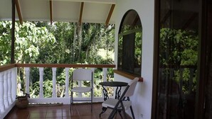 A covered balcony with a white railing, a table, and two chairs. - Costa Rican Paradise (La fortuna)