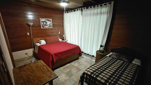 A bedroom with two beds, a wooden headboard, a bedside table, a lamp, and a framed picture on the wall. - Costa Rican Paradise (La fortuna)