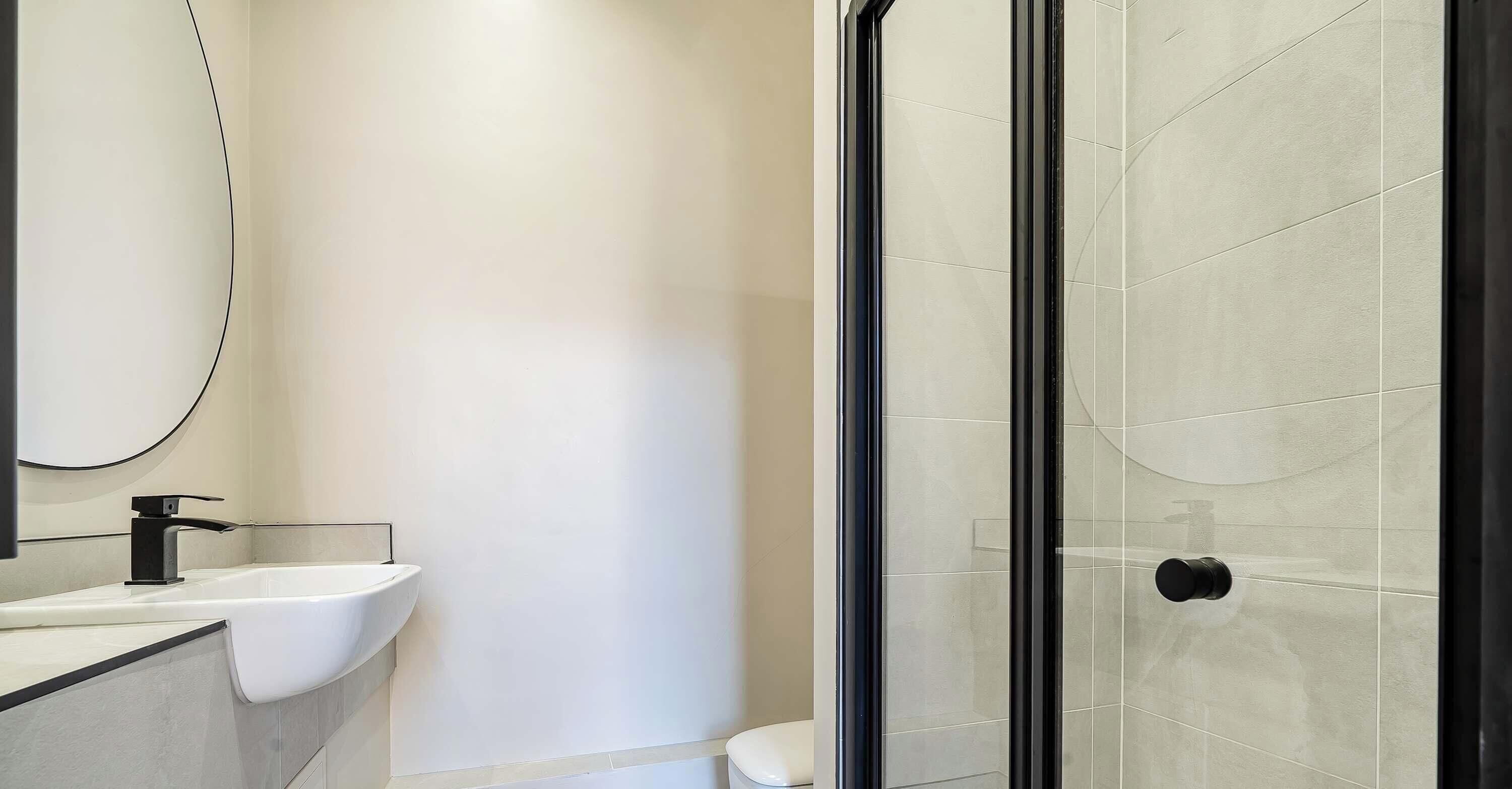 Un baño moderno con un lavamanos blanco, un inodoro y una cabina de ducha con paredes de vidrio.