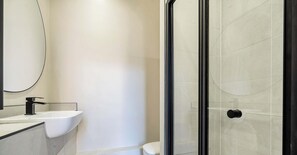 A modern bathroom with a white sink, a toilet, and a glass shower enclosure.