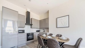A modern kitchen with a dining area, featuring a built-in oven, microwave, and a large stove. - Shore Thing - Relaxing Sea View Getaway (Portsmouth)
