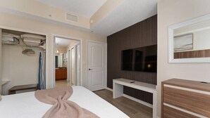 Een slaapkamer met een bed, een televisie, een kledingkast en een bankje.