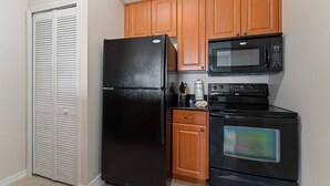 Una cocina con un refrigerador negro, gabinetes de madera, un microondas y un horno.