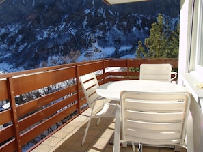Ein Balkon mit Holzgeländer, einem runden Tisch und vier Stühlen.