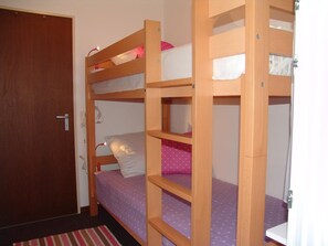 A bunk bed room with a wooden door and a striped rug. - Clabina 19 # 4-bed apartment, Bad, WC 4-Bettwohnung, Bad, WC by Interhome (Leukerbad)