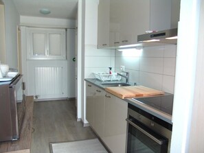A compact kitchen with a built-in oven, a countertop with a sink, and a window above the sink. - Clabina 19 # 4-bed apartment, Bad, WC 4-Bettwohnung, Bad, WC by Interhome (Leukerbad)
