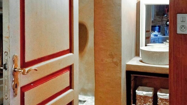 Un bagno con un lavandino bianco, uno specchio e una porta con maniglia in ottone.