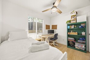 Ein Schlafzimmer mit Bett, Schreibtisch, Stuhl und Bücherregal.