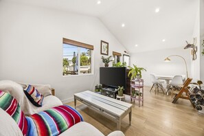Ein Wohnzimmer mit einer Couch, einem Fernseher und einem Essbereich mit Stühlen und einem Tisch.