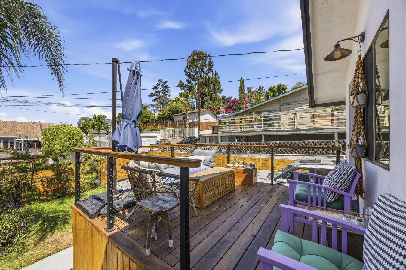 Eine Holzterrasse mit Gartenmöbeln, einem überdachten Sitzbereich und Blick auf ein Wohngebäude.