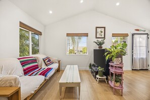 A spacious living room with a sofa, a coffee table, a TV, and a plant stand. - Cozy Highland Park Family Home w/ EV (Los Angeles)