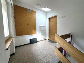 A hallway with a wooden door, a white wall, a ceiling light, and a window. - Diana 9 # 3-bed apartment, Dusche, WC 3-Bettwohnung, Dusche, WC by Interhome (Leukerbad)