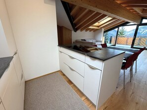 A kitchen with a wooden ceiling, white cabinets, and a dining area with red chairs. - Diana 9 # 3-bed apartment, Dusche, WC 3-Bettwohnung, Dusche, WC by Interhome (Leukerbad)