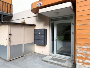 A building entrance with a glass door, a mailbox, and a metal storage unit. - Diana 9 # 3-bed apartment, Dusche, WC 3-Bettwohnung, Dusche, WC by Interhome (Leukerbad)