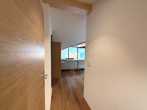 Un pasillo que conduce a una habitación con cama, ventana y puerta.