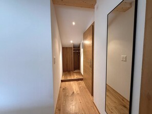 Ein schmaler Korridor mit Holzboden und weißen Wänden.