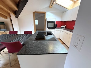 A modern kitchen with a built-in stove, a microwave, and a red backsplash. - Diana 9 # 3-bed apartment, Dusche, WC 3-Bettwohnung, Dusche, WC by Interhome (Leukerbad)