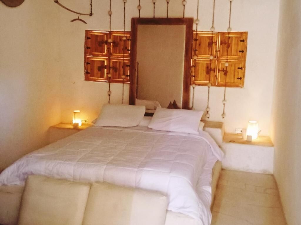 Een slaapkamer met een bed, twee nachtkastjes en een houten hoofdbord met een spiegel.