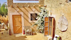 A rustic building with a wooden door, a window, and a wall-mounted light fixture. - tanirt ecolodge (Siwa)