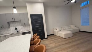 A modern kitchen with white cabinets, a black door, and a dining area with brown chairs. - Upscale 3BR Townhome Near the World Cup • Sleeps 8 (Decatur)