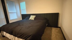A bedroom with a large bed, a headboard, and two windows with blinds. - Upscale 3BR Townhome Near the World Cup • Sleeps 8 (Decatur)