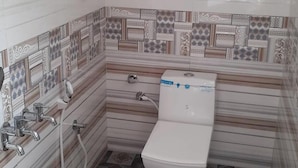 A small bathroom with a toilet, a shower, and a sink.