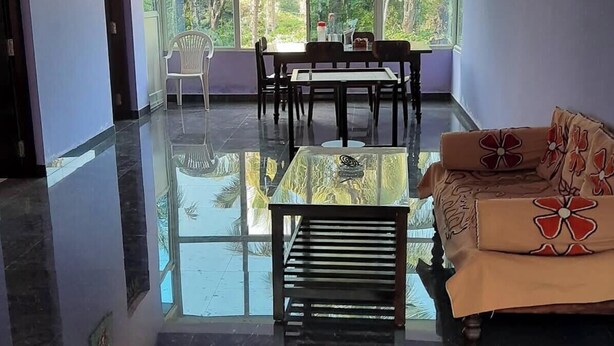 A spacious room with a dining table, chairs, a sofa, and a ceiling fan.