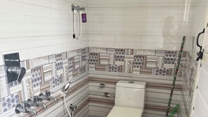 A bathroom with a toilet, shower, and hand dryer.