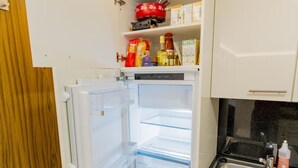 Eine kompakte Küche mit Einbaukühlschrank, Spüle und Holztür.