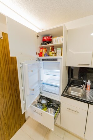 Eine kompakte Küche mit Einbaukühlschrank, Spüle und Holztür.