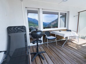 Ein Balkon mit Tisch, Stühlen, einem Grill und Blick auf Berge.