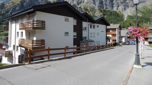 Ein modernes Hotel mit Balkonen, einer weißen Fassade und Blick auf die Berge.