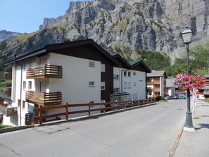Ein modernes Hotel mit Balkonen, einer weißen Fassade und Blick auf die Berge.