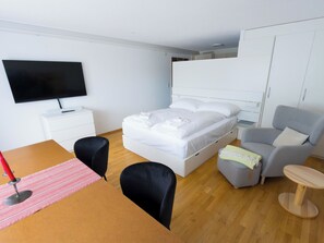 A hotel room with a bed, a TV, a desk with a chair, a sofa, and a small table. - Olympia 54 # 2-bed apartment, Dusche, WC 2-Bettwohnung, Dusche, WC by Interhome (Leukerbad)
