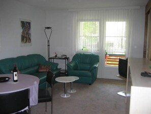 A living room with a green sofa, a small round table, and a lamp. - La Promenade 22 # 2-bed apartment, Dusche, WC 2-Bettwohnung, Dusche, WC by Interhome (Leukerbad)