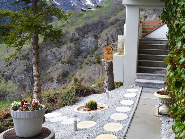 A mountain view with a wooden sculpture, a staircase, and a garden with circular stepping stones. - Albina 43 # 4-bed apartment, Dusche, WC 4-Bettwohnung, Dusche, WC by Interhome (Albinen)
