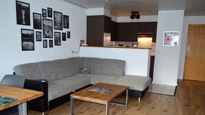 A living room with a grey sofa, a wooden coffee table, and a kitchen in the background. - Albina 43 # 4-bed apartment, Dusche, WC 4-Bettwohnung, Dusche, WC by Interhome (Albinen)