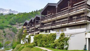 A multi-story hotel with balconies, a pathway, and a mountainous backdrop. - Albina 43 # 4-bed apartment, Dusche, WC 4-Bettwohnung, Dusche, WC by Interhome (Albinen)