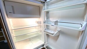 Et åbent køleskab med flere hylder og en vanddispenser.