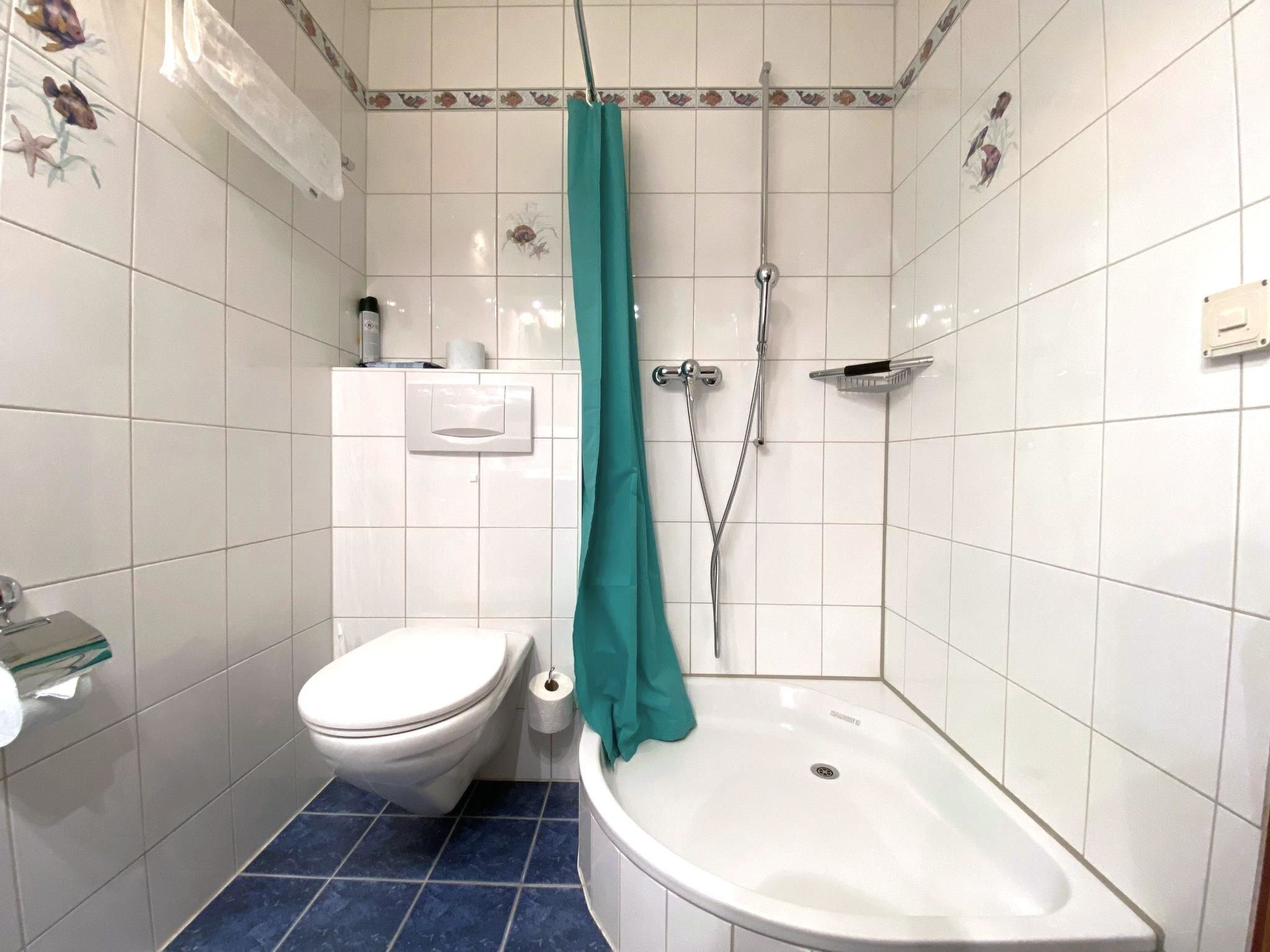 A bathroom with a toilet, a shower with a curtain, and a sink.