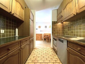 A narrow kitchen with wooden cabinets and a tiled backsplash. - Lärchenwald 1706 # 6-bed apartment, Dusche, WC 6-Bettwohnung, Dusche, WC by Interhome (Leukerbad)