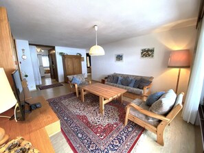 Ein Wohnzimmer mit einer Couch, zwei Sesseln, einem Couchtisch, einem Teppich und einer Lampe.