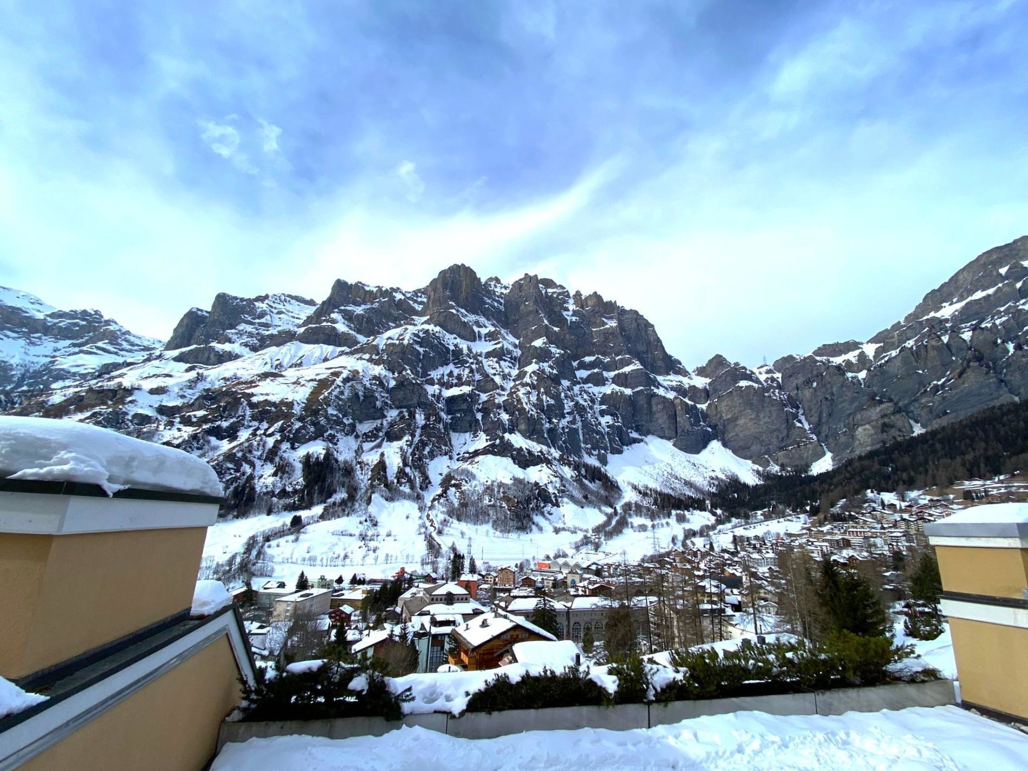 A mountainous landscape with snow-covered peaks and a town below.