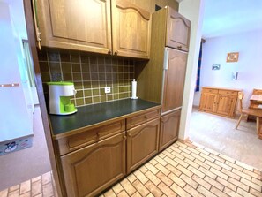 Une cuisine avec des meubles en bois, un plan de travail noir et un appareil électroménager vert.