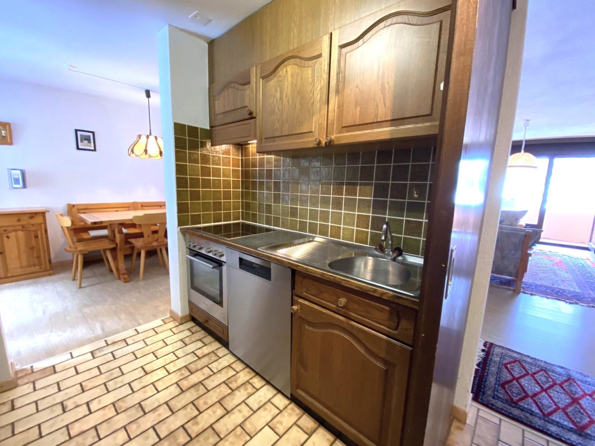A kitchen with wooden cabinets, a dishwasher, and a tiled backsplash.
