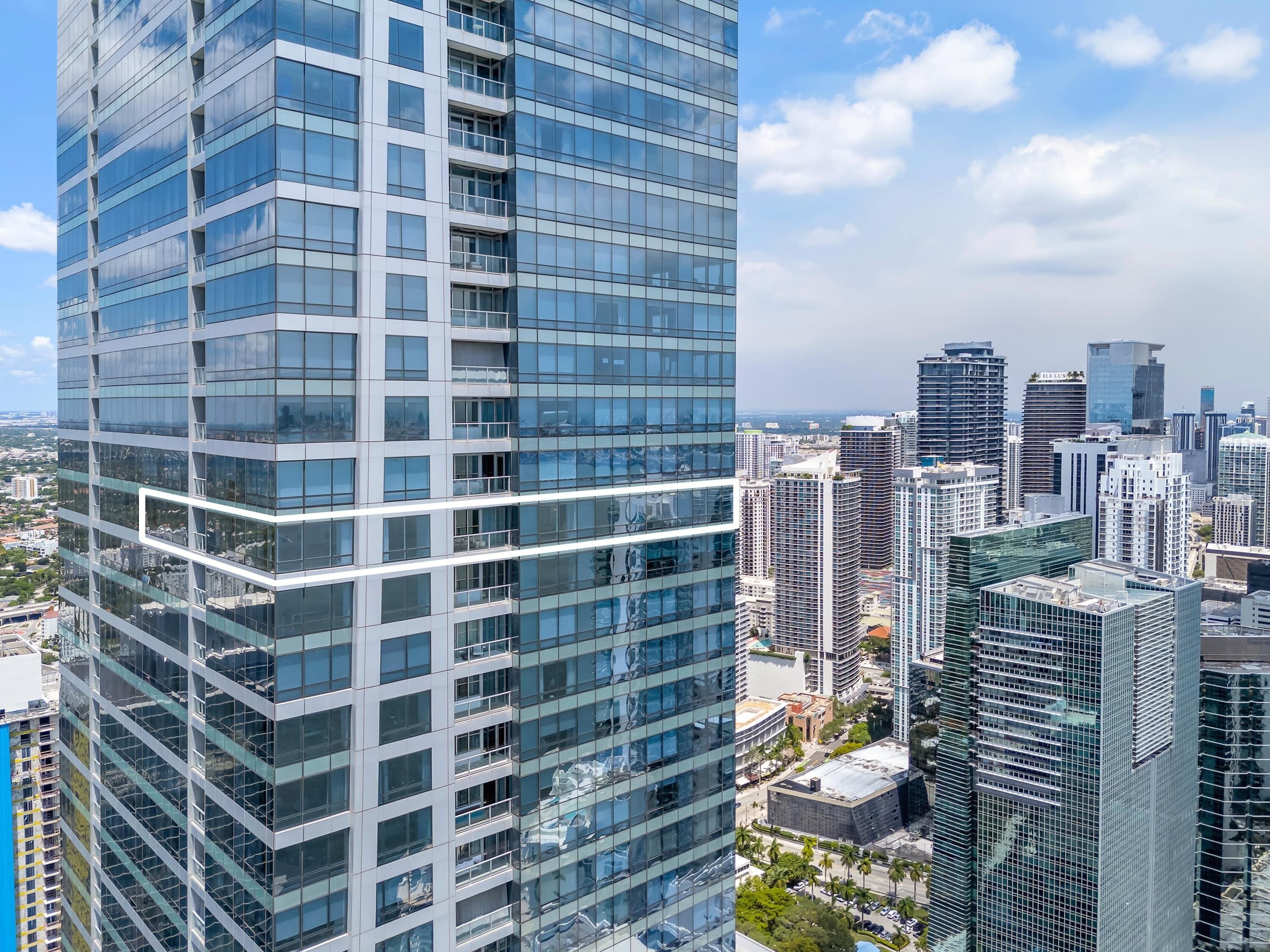 A high-rise building with a modern glass facade, surrounded by other tall buildings in a cityscape.