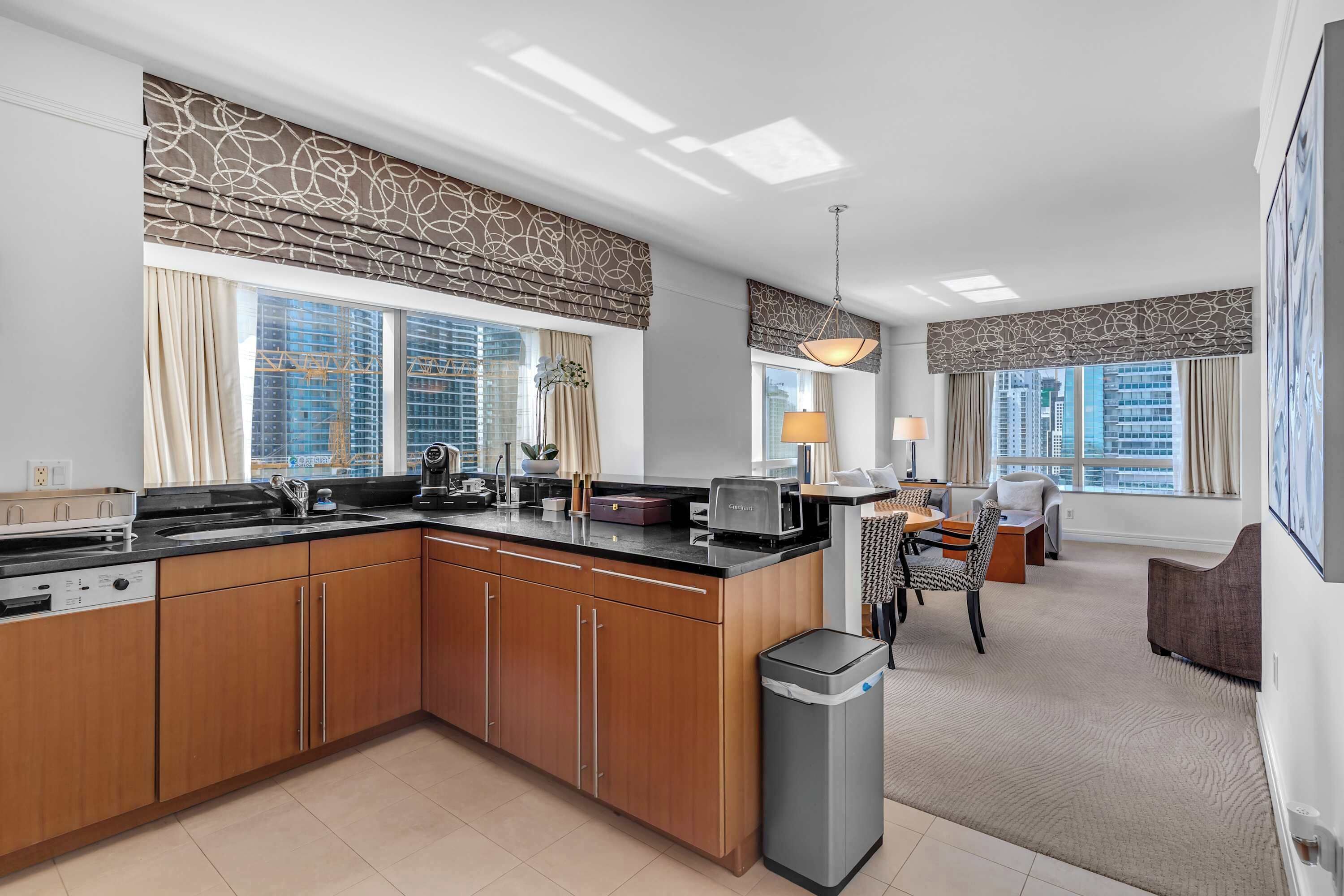 A modern kitchen with a central island, built-in appliances, and large windows with city views.