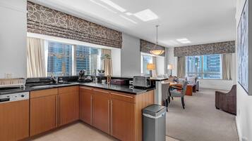 A modern kitchen with a central island, built-in appliances, and large windows with city views.
