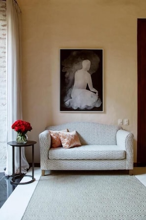 A living room with a sofa, a framed artwork, a vase with red flowers, and a patterned rug. - Ancalá Casa De La Renta (Cartagena de Indias)